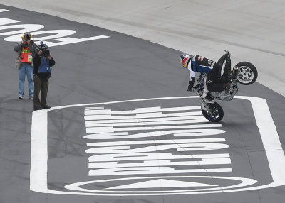 MOTORCYCLE STUNT RIDER,  CHRISTIAN PFEIFFER, DEMONSTRATES A STOPIE BEFORE THE RACE
