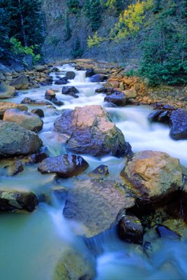 (WES22) Stream  contaminated with mining runnoff precipitating metalic oxides, on rocks, Ouray, CO