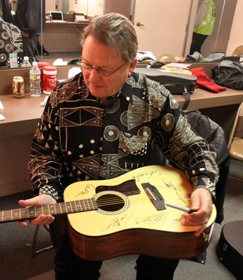 David LaFlamme signs commemorative guitar for Chico community radio station KZFR auction