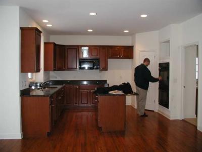 kitchen- brushed nickel knobs and pantry handle cherry paprika cabinets, black appliances, cherry stained flooring
