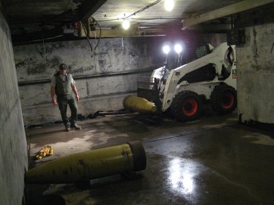 Park Service maintenance crew using Bobcat to move 16-inch shells into magazine