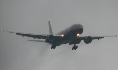 A United 777 appears from the clouds