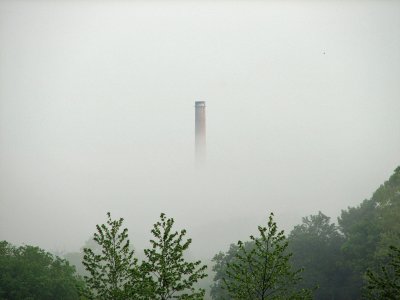 A smokestack from the power station floats in the fog