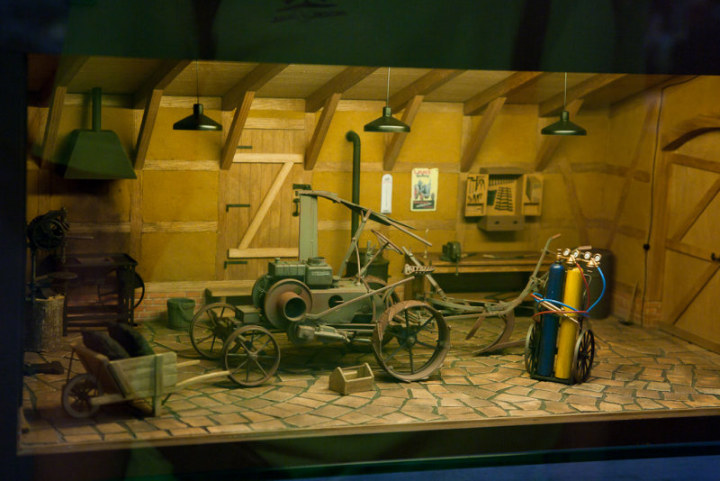 Titteskap-diorama; en gammel landbruksmaskin i garasje