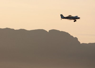 Crop Duster spraying farm fields in Mesilla Valley with Organ Mountains in background