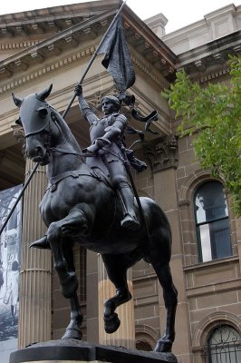 Bronze statue of Jeanne d'Arc in her battle armour on her trusty steed holding her banner.