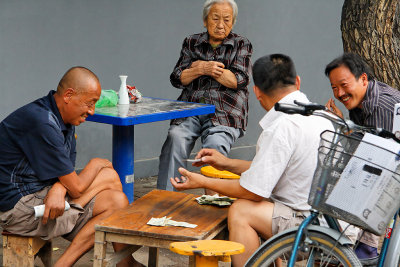 Residents of the Hutong gathering on the street and ignoring the parade of tourists