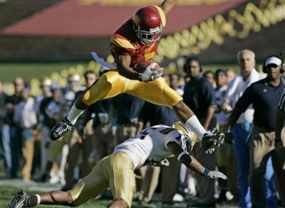 Reggie Bush leaps over UCLA defender Marcus Cassel as he runs for a 9-yard gain in the first quarter.jpg