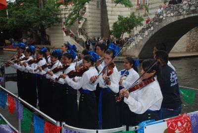 SEVERAL LOCAL MARIACHI BANDS FLOAT THE RIVERWALK, PULL UP TO A GROUP OF PEOPLE AND SERANADE THE CROWDS