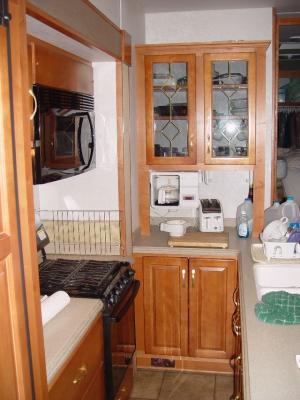 KITCHEN AREA WITH REFRIG ON LEFT, CONVECTION MICROWAVE, RANGE AND OVEN, COFFE MAKER AND SINK WITH STORAGE ABOVE AND BELOW