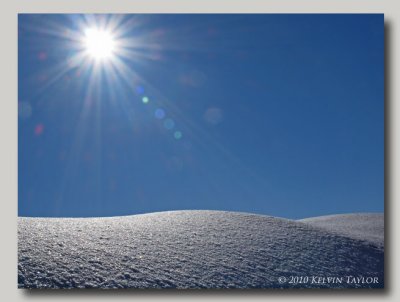 Sunrays over a snowy hill