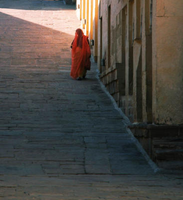 An old woman walks the passage towards the temple