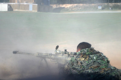 A Special Forces sniper kicks up dust and causes the ground to shake while giving a demonstration with his M82 Barrett .50-caliber sniper rifle. Firing at a car several hundred yards away, he hits the vehicles gas tank with several consecutive incendiary-tipped .50 caliber rounds, causing the automobile to become engulfed in a rolling fire.