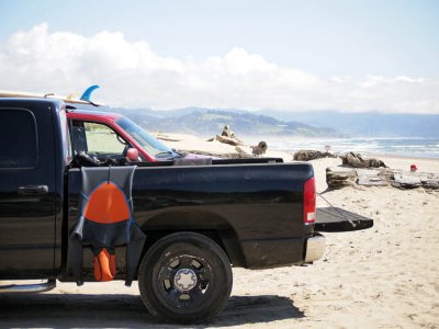 Surfers wetsuit dries on side of truck.