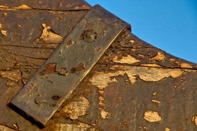Metal with bolts and old painted wood against blue  sky