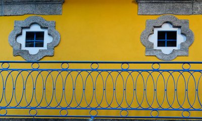 Twin windows, yellow wall, blue veranda
