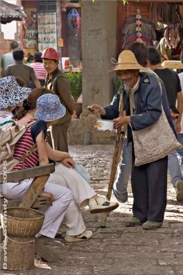 LiJiang - old city.  Beggar and tourists.  He seemed quite happy!