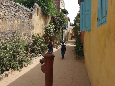 Children walking down a path. Many of the colonial houses on Goreé Island are painted in pastel colors.