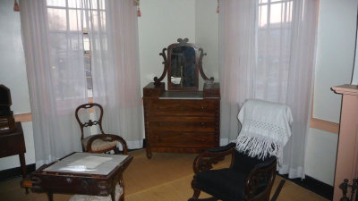 The room contains some of her jewelry in a jewelry box and a traveling desk in the center of the room.