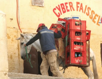 Man hauling cases of Coca Cola through the medina on the back of a horse.