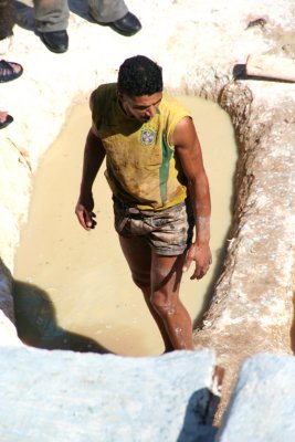 Barefoot workers in shorts pick up skins from the bottom of the dyeing vats with their feet, then work them manually.