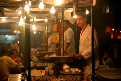 Chefs preparing food at a food concession stand in Place Djemaa El-Fna.