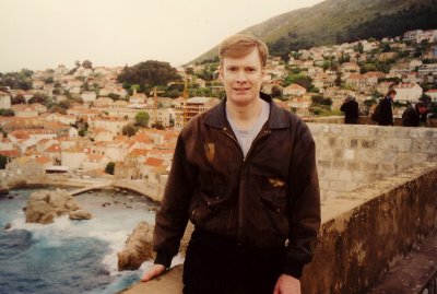 Me posing along Dubrovnik's defensive wall with waves of the Adriatic Sea breaking below.