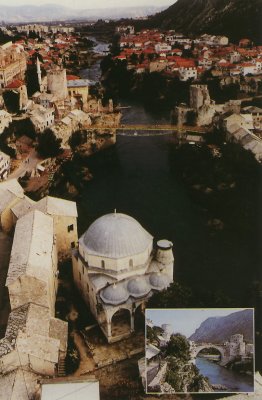 View of the Old Bridge of Mostar with a massive mosque in the foreground.