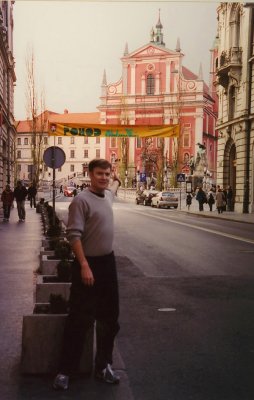 Me standing on a Ljubljana street with Preeren Square and the Franciscan Church in the background.