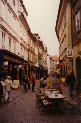 A quaint, narrow street in Ljubljana with an outdoor restaurant on the cobblestone street.