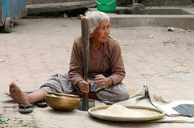 Lady pounding rice, Nepal.