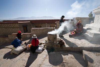 Vendors on the left, worshipper in the back, performers on the right with burning incense in the front.