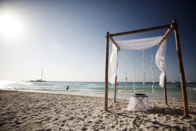 Bamboo arch with floral garlands hanging off the back. Photo by Brandon & Eliesa, www.photogen-inc.com