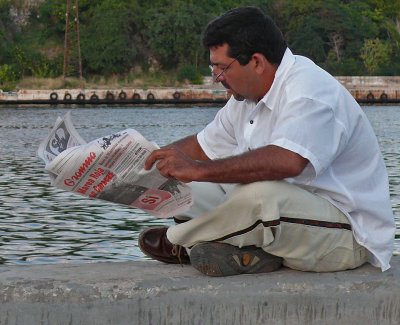 Reading Newspaper on Harbor Wall
