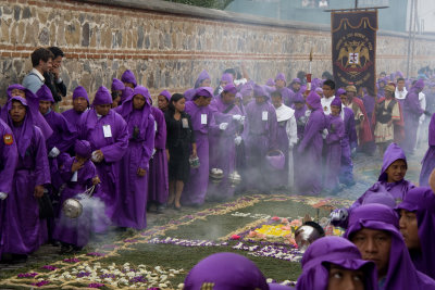The purple clad cucuruchos march beside many alfombras
