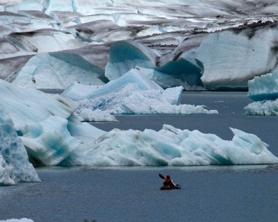 Kayaker weaving through the icebergs near the face of the Mendenhall Glacier