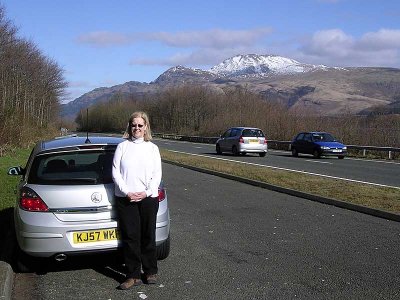 JoAnn and our rental car near Loch Lomond, notice the cars on the wrong side of the road to her right