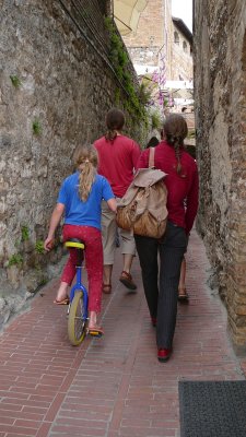 family with unicyclist daughter in small san gimignano street (R)