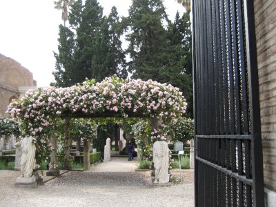 beautiful rose-covered entryway to roman baths with headless statues (G)