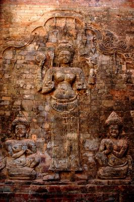 four-armed Lakshmi, Vishnu's consort, holding her attributes.  Attendants kneel in prayer at the feet of the goddess
