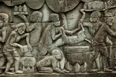 cooks prepare a banquet, lowering an animal into a cauldron