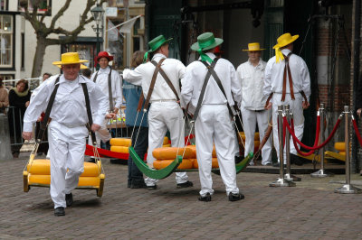 dressed in traditional white garb, cheese porters carry the cheese away in barrows after it has been weighed