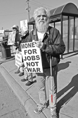 Man with red tipped cane and sign money for jobs not for war