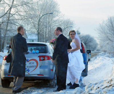 Shot through the windshield of our car... We had just parked by the side of the road when 2 vehicles pulled up right in front of us and these people got out. The man on the left is a photographer carrying his gear. My guess is that they were discussing doing a photo shoot in this area. Note the boots on the bride...