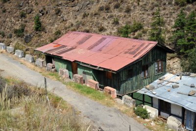House with a red tin roof built on stilts, Chhuzom