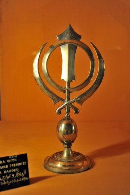 Small silver chakra with swords displayed on a stand presented by the Sikh Grud-wada Nanded