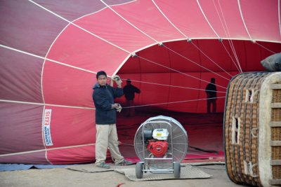 Ground crew members inspect the inside of the balloon as it is inflated with cold air