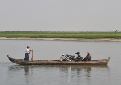 Wooden row boat ferrying a motorbike across the Irrawaddy River from Mingun