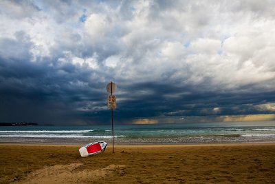 Storm approaching Manly with surfboard and sign