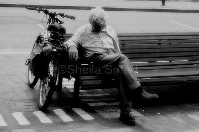 Man with bike on bench mono